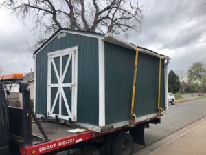 A shed being transported on a flatbed tow truck by A-ROD Towing in Denver, CO.