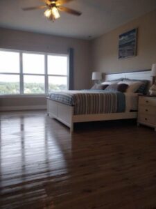 A clean bedroom with a large window and a gleaming, freshly cleaned floor by Peoria Cleaning Pros, LLC in East Peoria, IL.