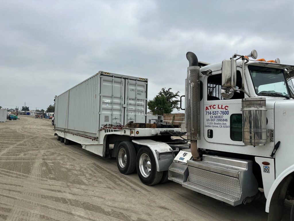 Affordable Towing LLC transporting a white shipping container on a flatbed trailer in Anaheim, CA.