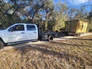 A shipping container on a trailer being towed by a pickup truck from Tiki's Towing LLC in Jacksonville, FL.