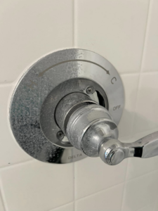 A shower faucet showing hard water stain removal in progress by Idaho Gem Cleaning in Caldwell, ID.