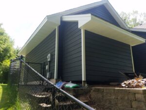 A side view of a house with dark gray horizontal siding and white soffit installed by Triton Exteriors in Maple Grove, MN.