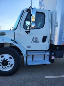 The side of a Top Notch Movers truck cab with license and DOT numbers visible in Lauderhill, FL.