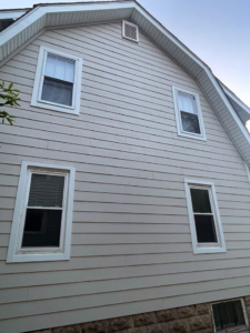 Side view of a residential home showcasing light-colored horizontal siding installed by Ideal Siding Nashville, TN.