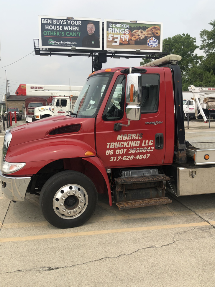 Side view of a red flatbed tow truck with Morris Trucking LLC branding in Indianapolis, IN.