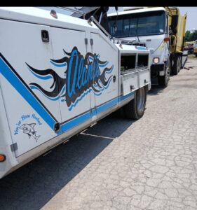 Side view of a white tow truck with Alanis Wrecker Service branding parked in San Antonio, TX.
