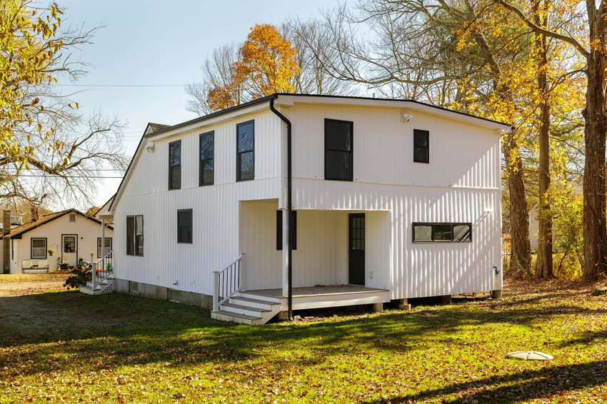 Side view of a modern white house with vertical siding installed by Atlantic Roofing and Siding in East Hartford, CT.