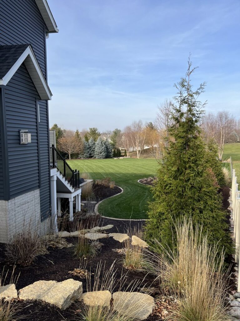 A neatly mowed side yard with fresh mulch in garden beds, showcasing Thompson Acres' work in Davenport, IA.