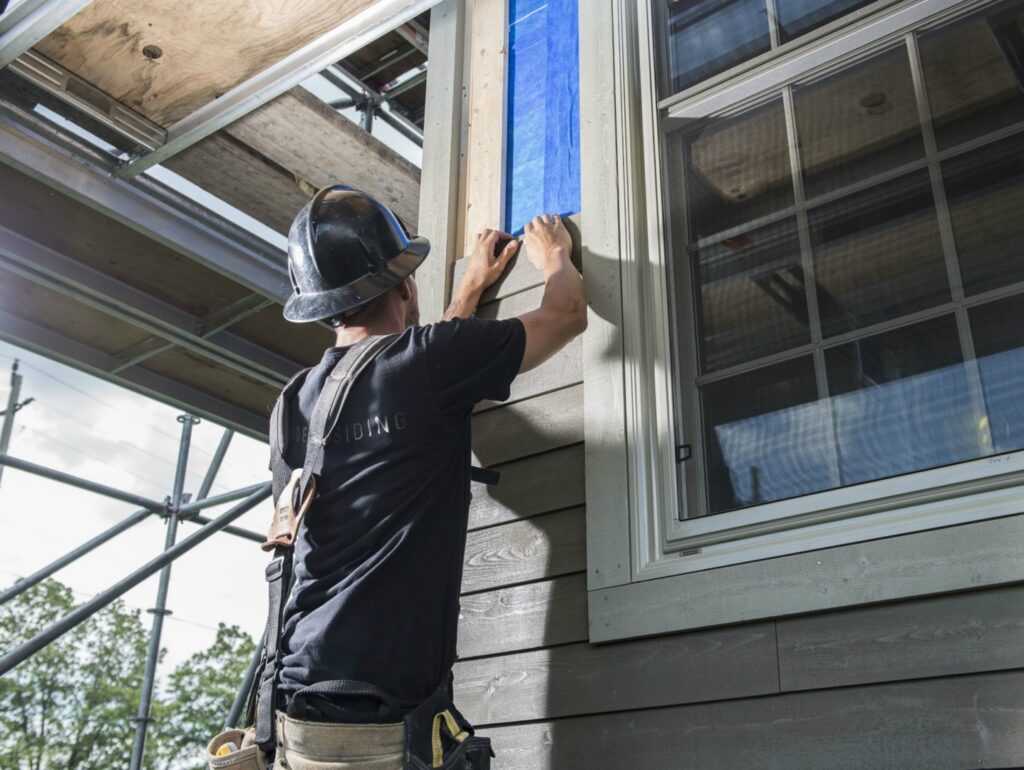 A siding contractor preparing a window for new siding installation by Ideal Siding Dallas, TX.