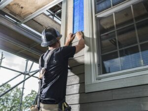 A siding contractor preparing a window for new siding installation by Ideal Siding Dallas, TX.