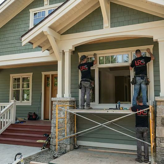 A crew from Lifetime Remodeling Systems installing siding and windows on a green house in Portland, OR.