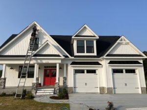 A worker installing white siding on a house, showcasing work by Cordell Exteriors Inc in Chesapeake, VA