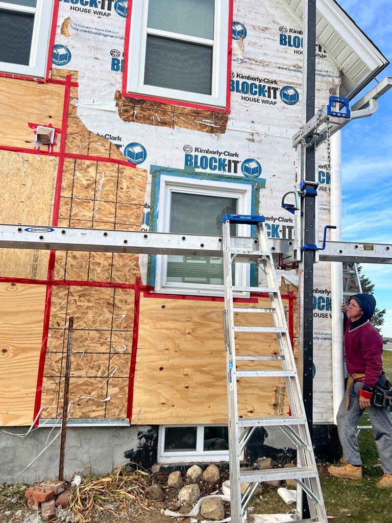 Siding installation in progress on a house, showing house wrap and plywood, by DJ Paz All Siding & Roofing Construction in Iowa City, IA
