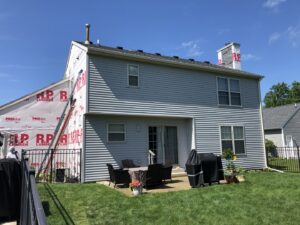 New light blue siding installation in progress on a house, with house wrap visible, by Freeman Exteriors in Danville, IL.