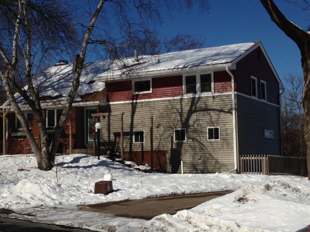 Siding installation in progress, featuring new red and beige siding and Tyvek wrap by Capital Siding, Windows & Roofing, Woodbury, MN.