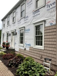 Siding installation in progress on a house, showing Tyvek house wrap and new shake siding by DL Roofing and Siding in New Haven, CT