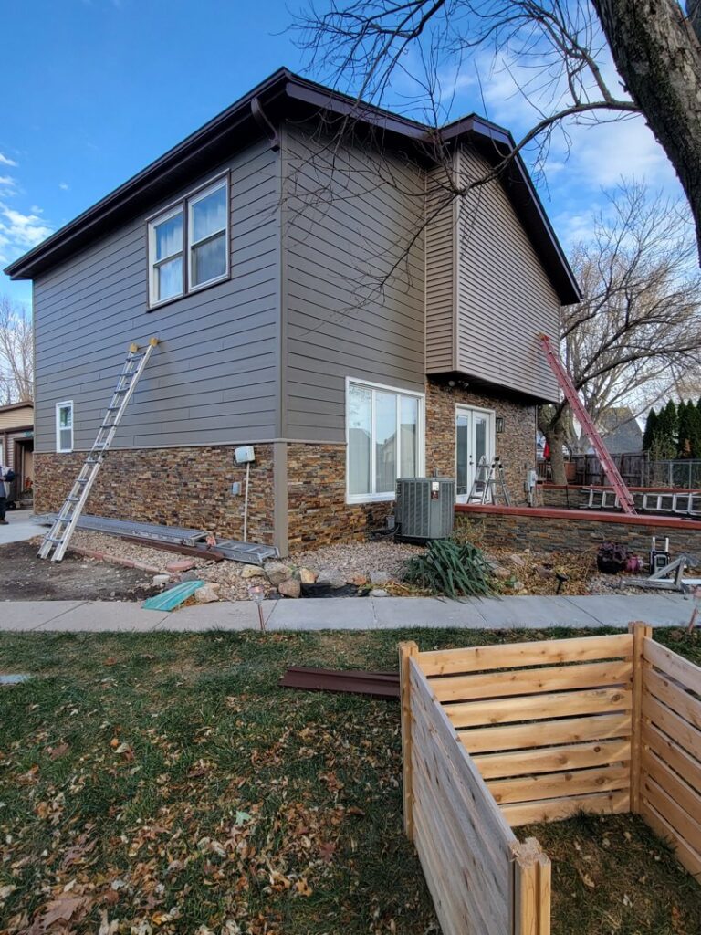 Siding installation in progress on a two-story home, showing horizontal siding and stone veneer by D.A. Siding & Windows in Grand Island, NE.