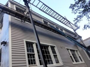 Workers installing light gray horizontal siding on a house using ladders and scaffolding by DL Roofing and Siding in New Haven, CT