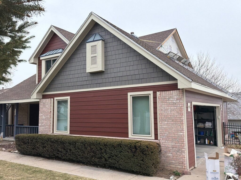A residential siding project featuring red and gray panels, with materials visible, by Bishop Exteriors in Omaha, NE.