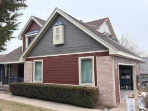 A residential siding project featuring red and gray panels, with materials visible, by Bishop Exteriors in Omaha, NE.