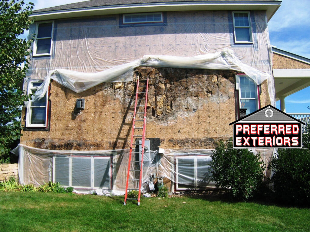 House exterior with old siding removed, exposing plywood sheathing and a ladder, work by Preferred Exteriors in Roswell, GA