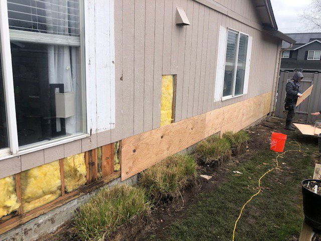 A worker installing new siding on a house, with insulation exposed, by Preferred Exteriors in Roswell, GA