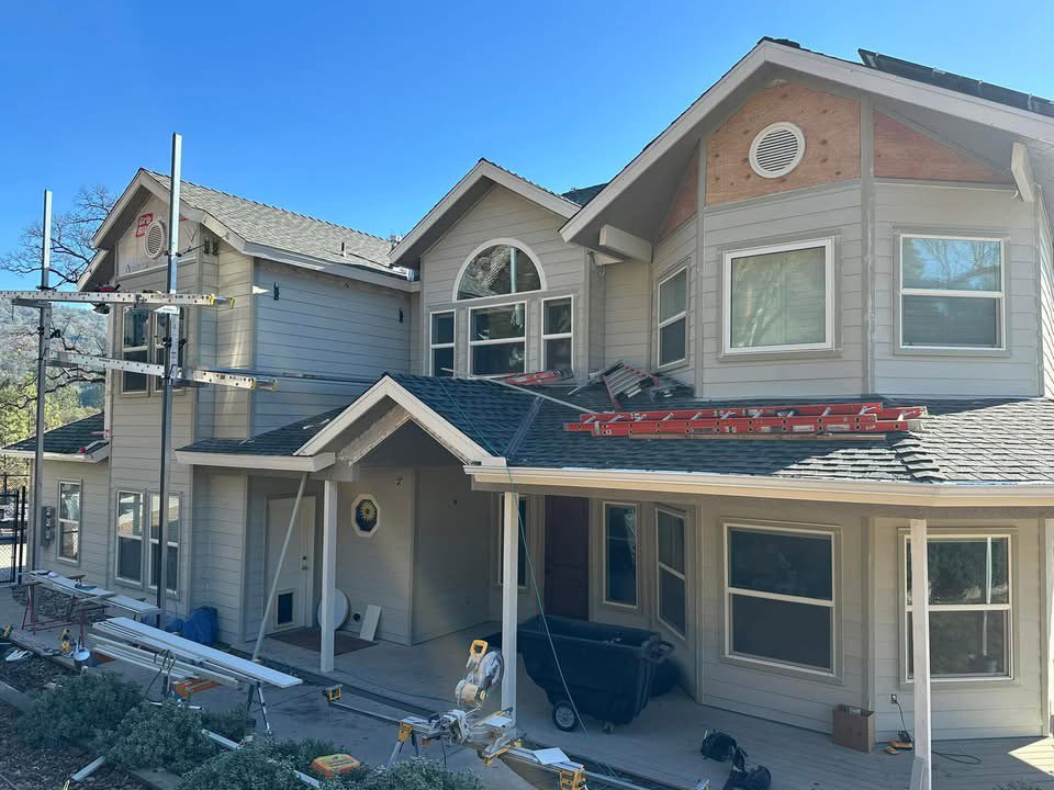 A large residential siding replacement project in progress with scaffolding and ladders by Bushco Contracting LLC in Fresno, CA.