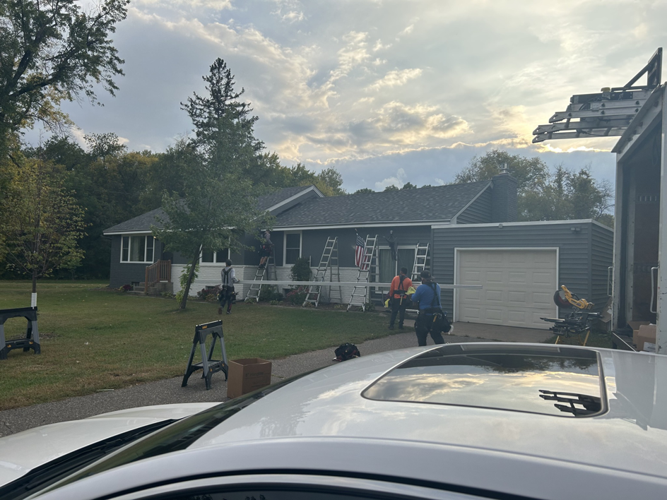 A siding and roofing crew actively working on a house exterior for PMC Company in Brooklyn Park, MN.