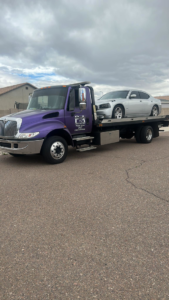 A silver car being transported on a purple flatbed tow truck by P&A towing & transport Llc in Phoenix, AZ