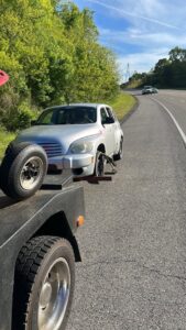 A silver car with a missing front wheel being loaded onto a flatbed tow truck by Tow Truck Company in Johnson City, TN.