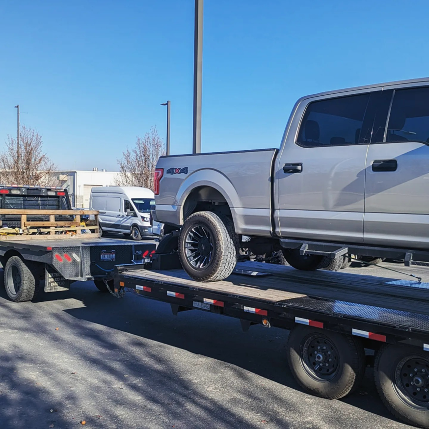 A silver Ford pickup truck loaded onto a flatbed trailer by Mountain Goat Rescue & Recovery LLC + Towing in Nampa, ID.