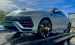 A silver Lamborghini Urus SUV securely loaded onto a TP Towing flatbed truck for luxury vehicle transport in Tampa, FL.