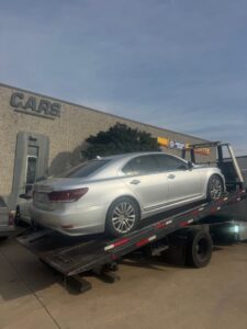 A silver Lexus sedan being loaded onto a flatbed tow truck by Towing Near Me 247 LLC in Irving, TX.
