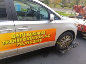 A silver minivan being hooked up to a tow truck's wheel lift for transport by Buffalo Towing Services in Buffalo, NY.