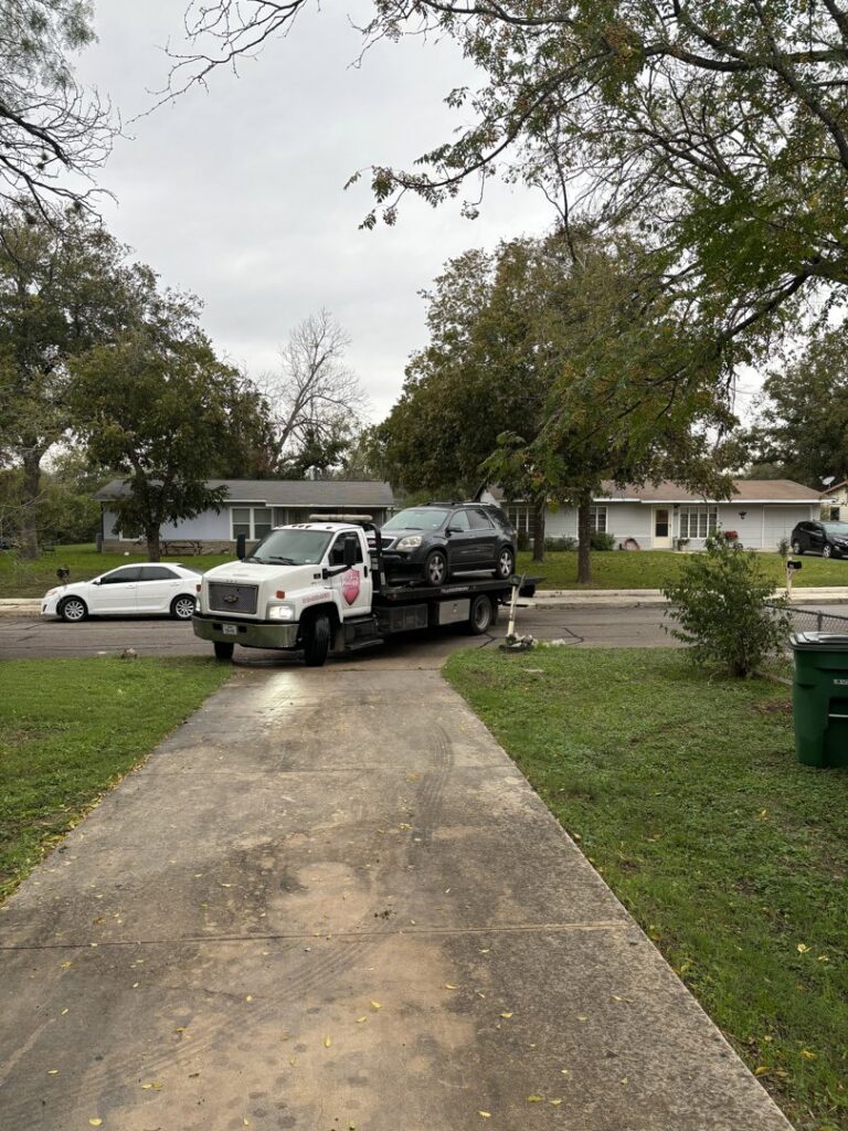 A silver pickup truck being loaded onto a flatbed tow truck by AB Towing & Transport in San Antonio, TX.