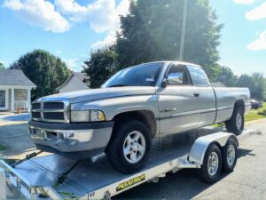 A silver pickup truck being transported on a car trailer by Snoork Towing in Charlotte, NC.