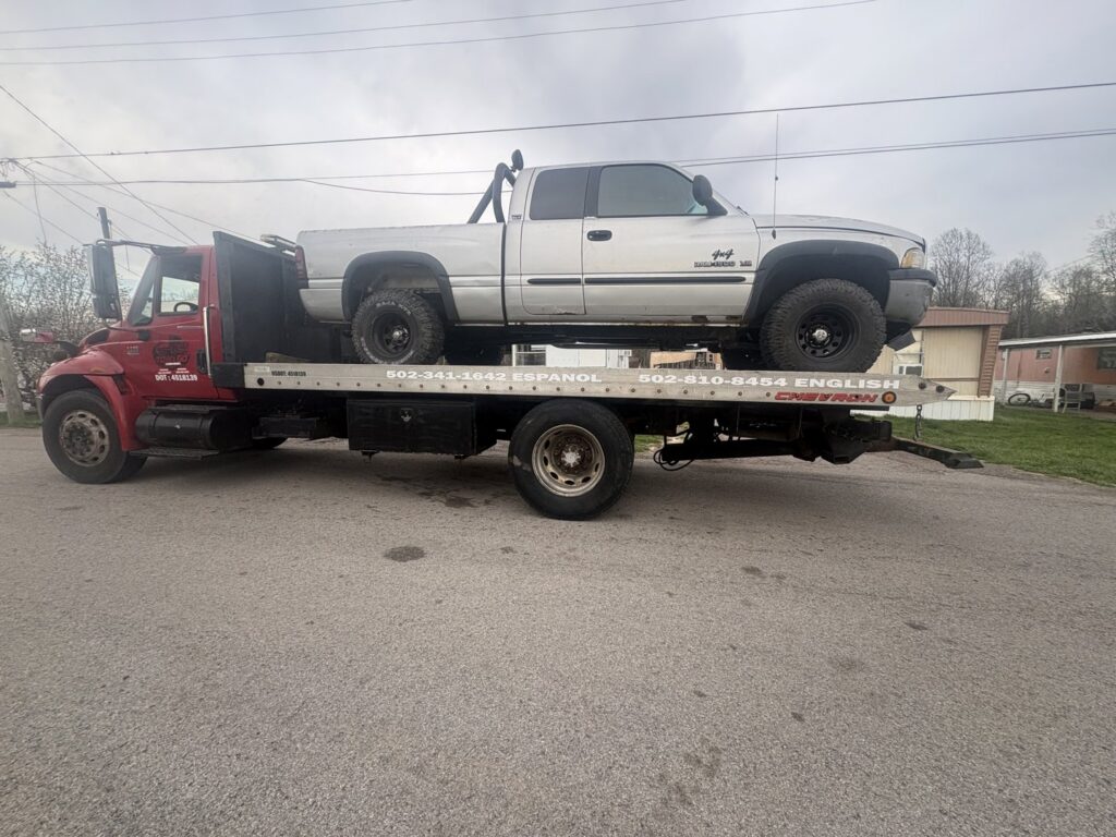 A silver pickup truck being transported on a flatbed tow truck by Tow & go in Louisville, KY.