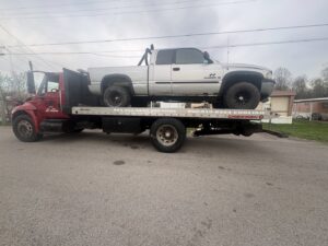 A silver pickup truck being transported on a flatbed tow truck by Tow & go in Louisville, KY.