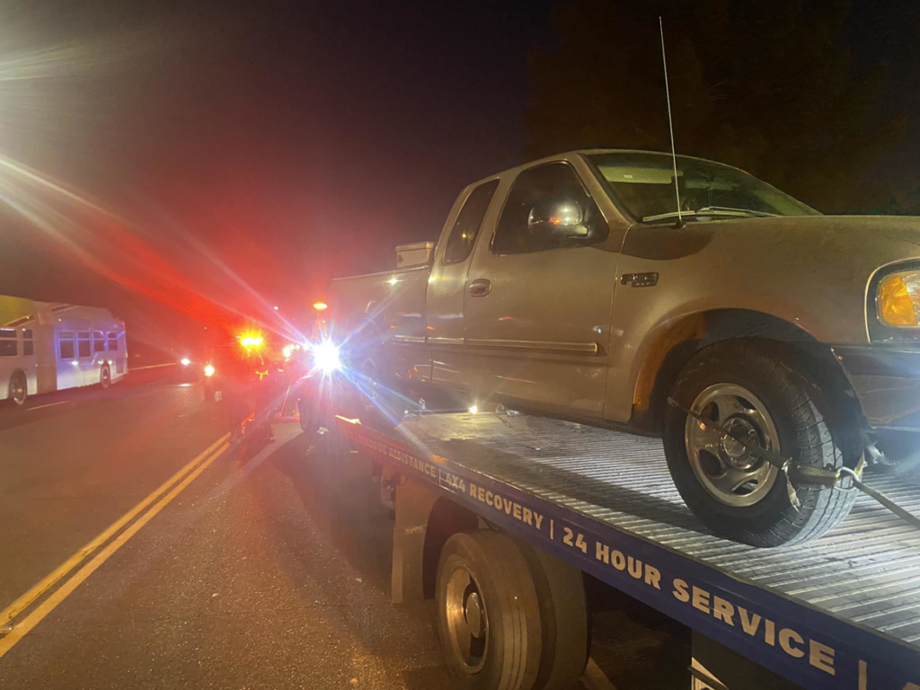 A silver pickup truck loaded onto a flatbed tow truck by CnD towing at night in Phoenix, AZ.