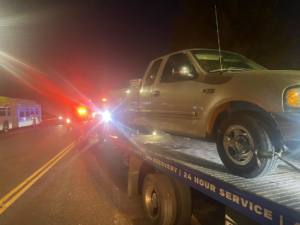 A silver pickup truck loaded onto a flatbed tow truck by CnD towing at night in Phoenix, AZ.