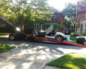 A silver Plymouth Prowler sports car being loaded onto a flatbed tow truck by Triple D's Towing in Sterling Heights, MI.