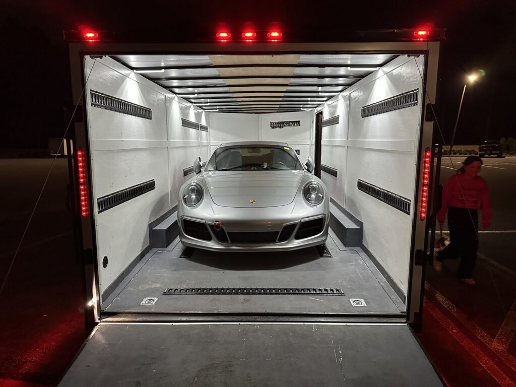 A silver Porsche sports car secured inside an enclosed trailer from B'ham Trailer Rentals in Alabaster, AL.