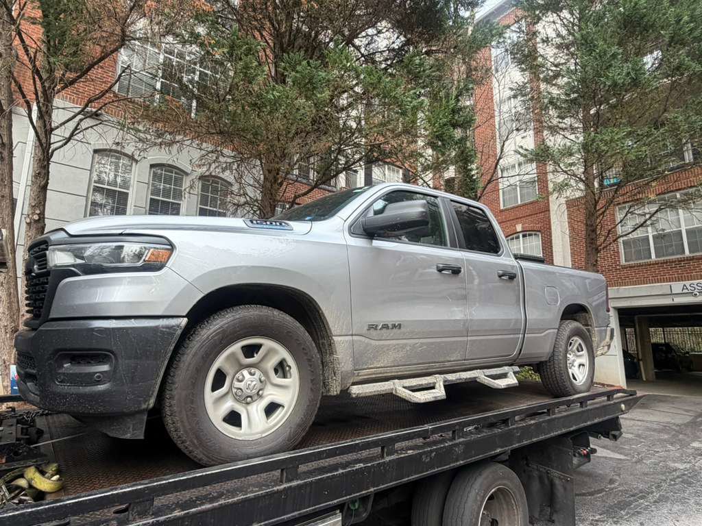 A silver Ram pickup truck being towed on a flatbed tow truck by Kingdom towing LLC in Atlanta, GA.