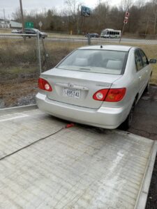 A silver sedan being pulled onto a flatbed tow truck for transport by Tow Truck Company in Johnson City, TN.