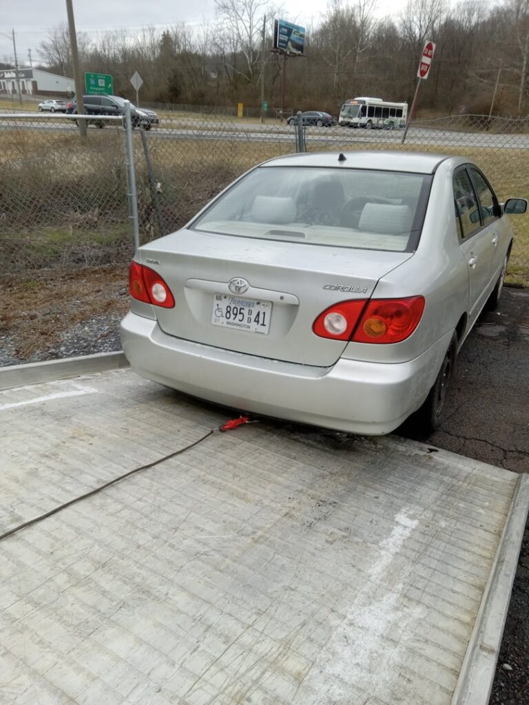 A silver sedan being pulled onto a flatbed tow truck for transport by Tow Truck Company in Johnson City, TN.