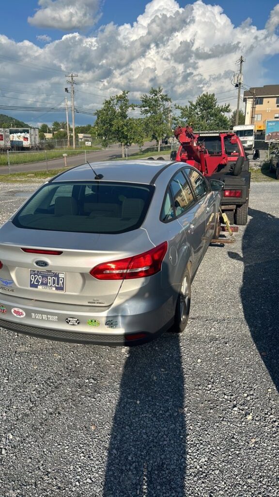 A silver sedan being towed by a red wrecker truck from Tow Truck Company in Johnson City, TN.