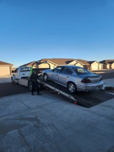 A silver sedan being loaded onto a flatbed tow truck by Carnahan's Towing & Repair Inc. in Great Falls, MT.