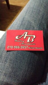 A silver sedan being transported on a flatbed tow truck by AB Towing & Transport in San Antonio, TX.