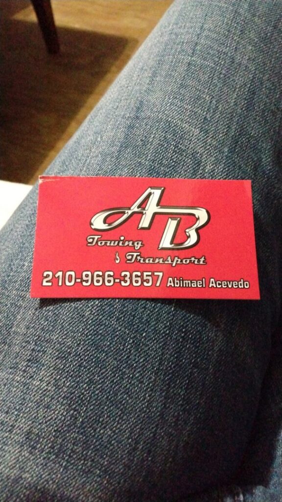 A silver sedan being transported on a flatbed tow truck by AB Towing & Transport in San Antonio, TX.