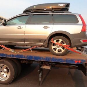 A silver station wagon with a roof cargo box secured on a flatbed tow truck by Fort Benning Towing in Columbus, GA